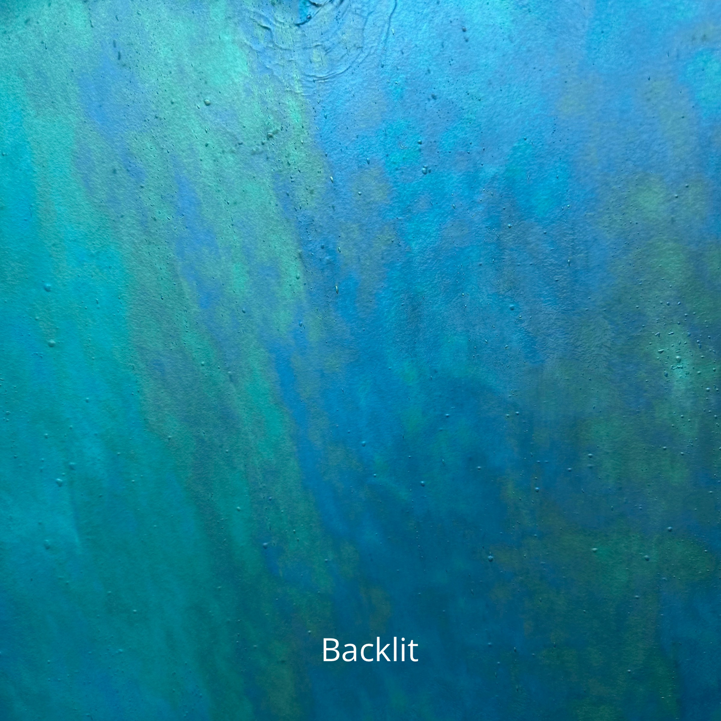 A backlit photo of a blue iridescent piece of stained glass.