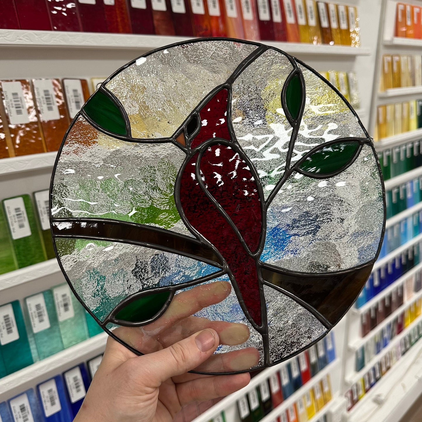 A stained glass window of a cardinal sitting on a branch.