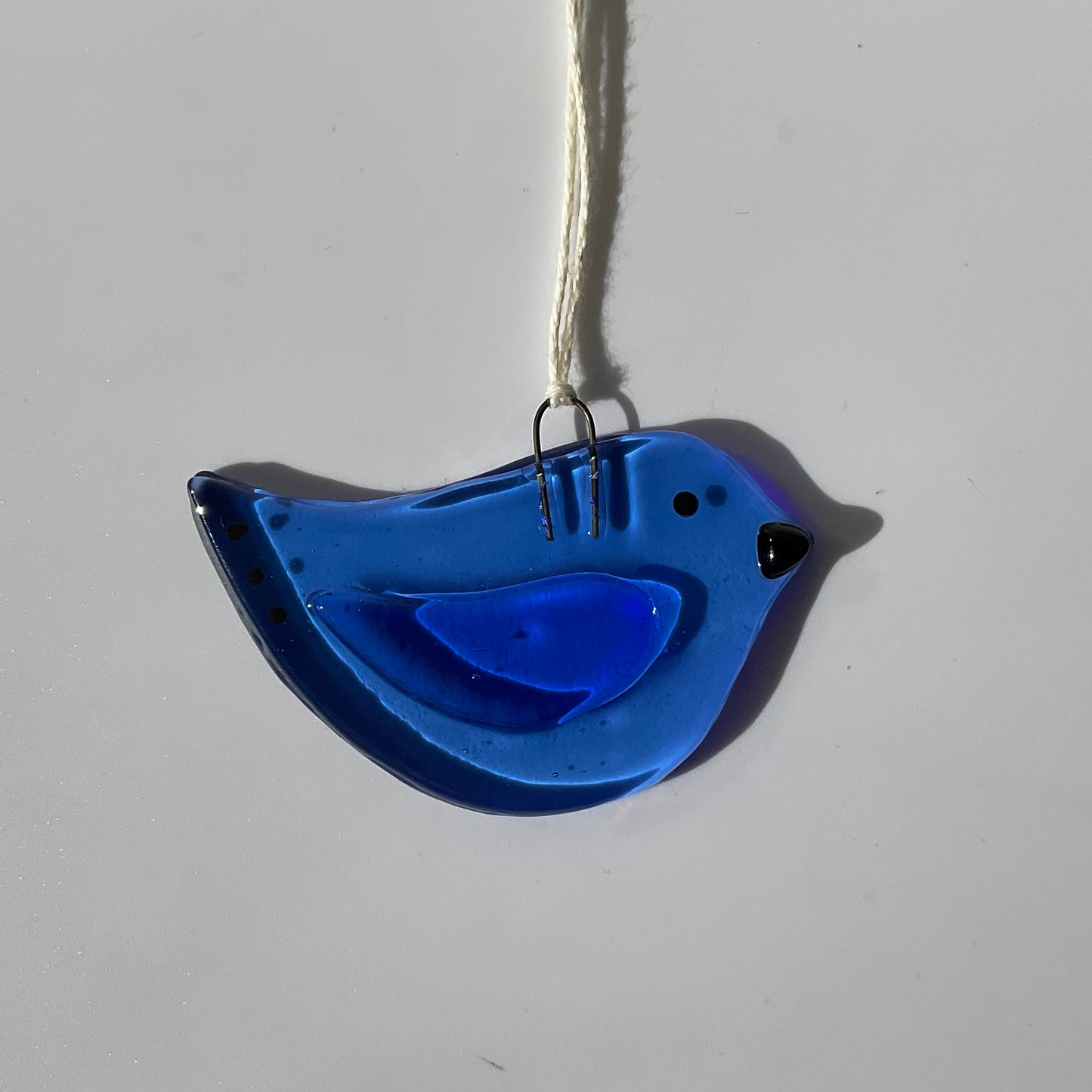 A blue fused glass bird ornament.