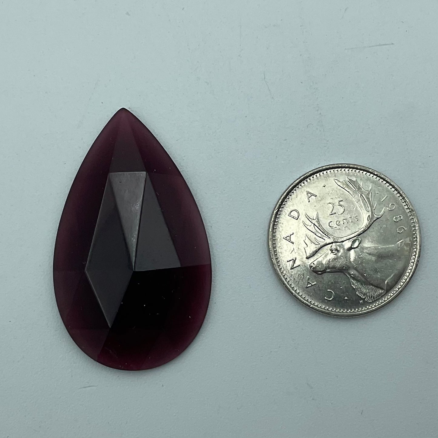A purple faceted teardrop glass jewel.