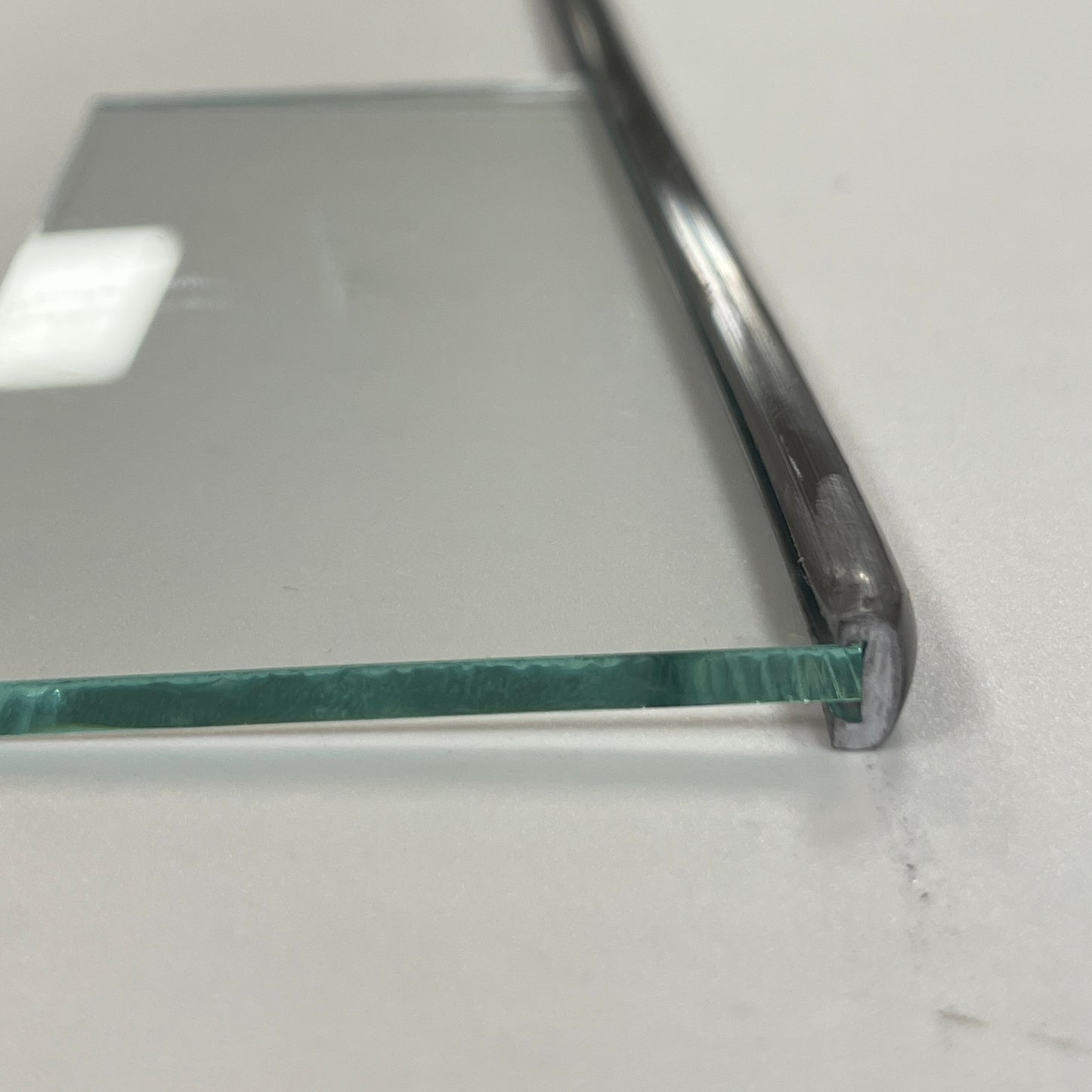 A piece of clear glass with a metal border lead, placed on a white surface.