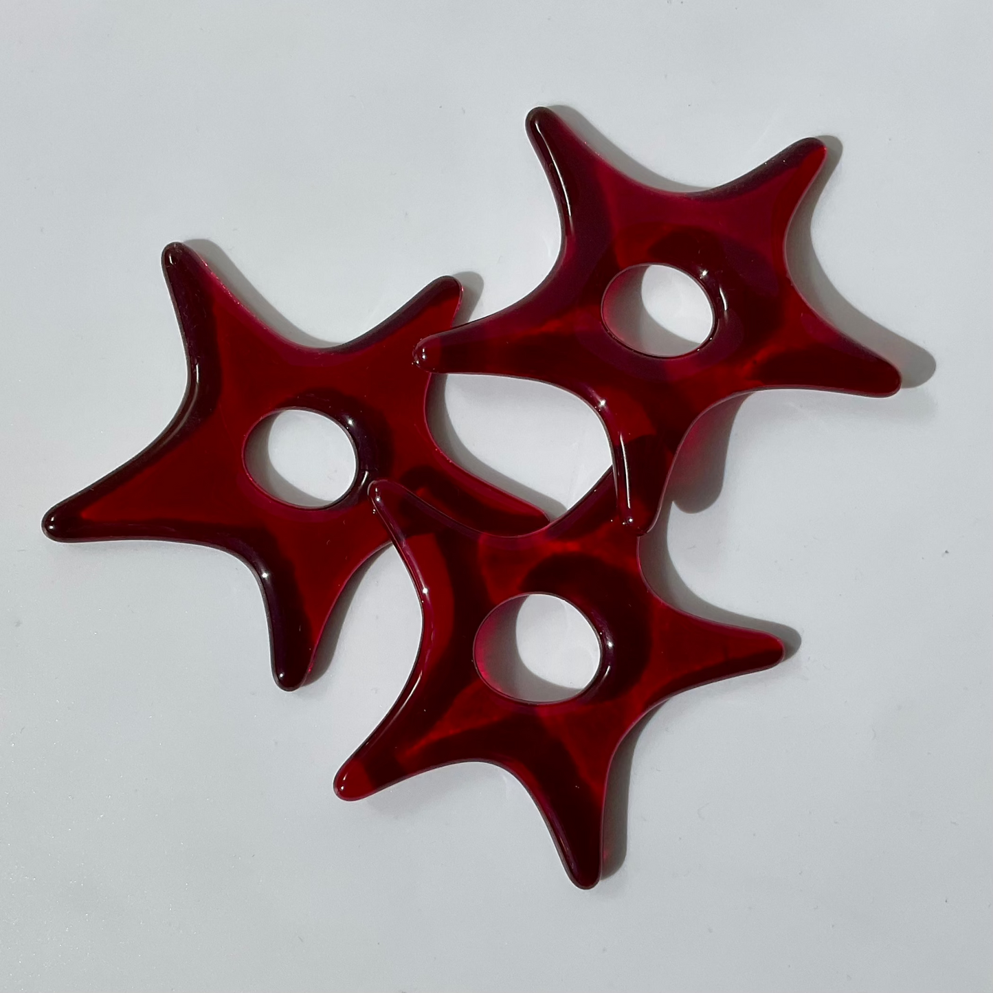 Three red fused glass star ornaments.