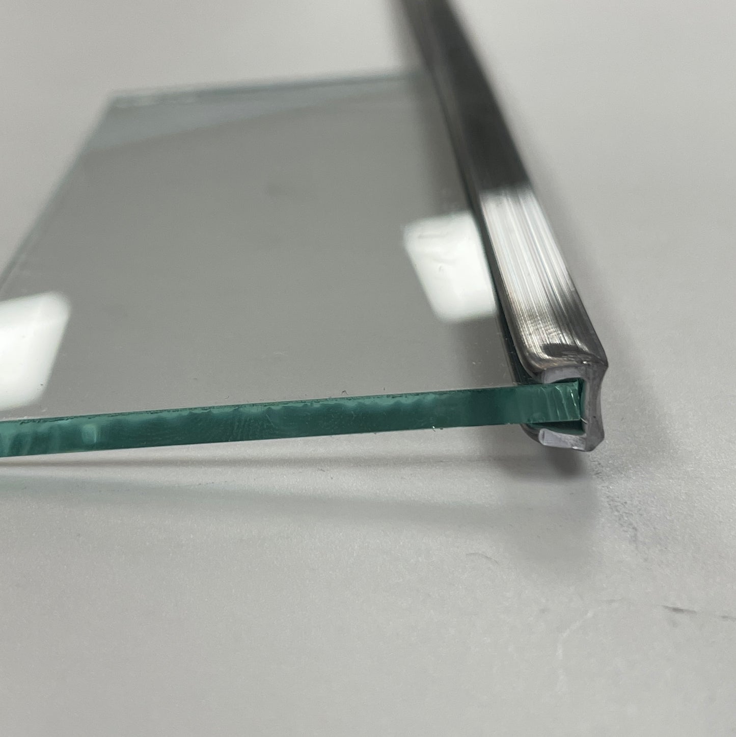 A close-up of a clear glass panel with a silver metal came frame, used for leaded glass window making.
