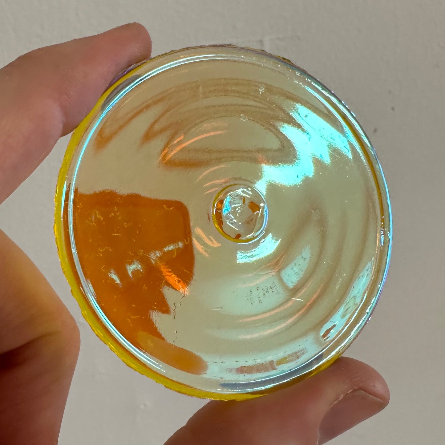 An iridescent signal yellow glass rondel for stained glass.