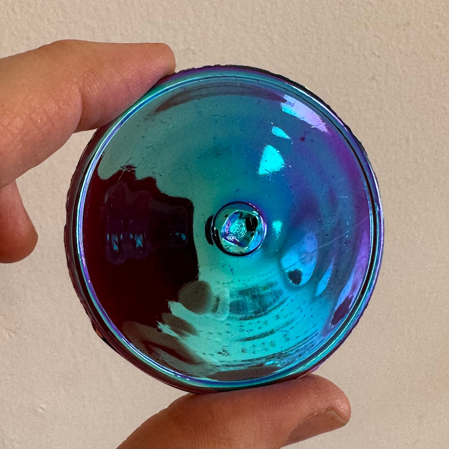A violet iridescent glass rondel for stained glass.