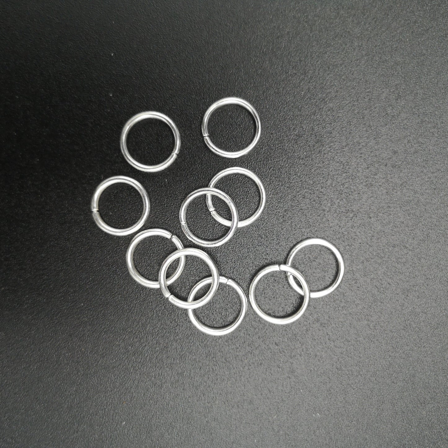 A pile of metal jump rings for hanging stained glass.