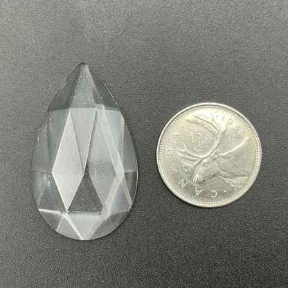 A clear faceted teardrop glass jewel.