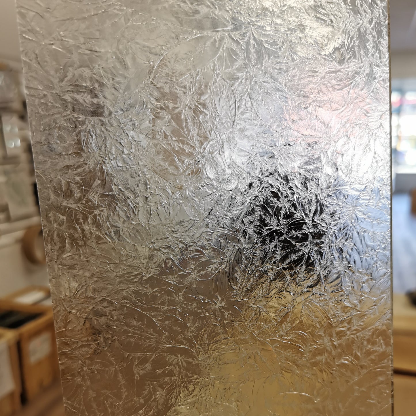 A close-up image of textured glass with a metallic reflection.