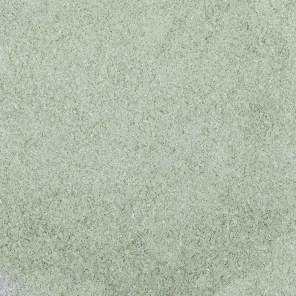 A close-up texture swatch of a light sage green material with a fine, granular surface.