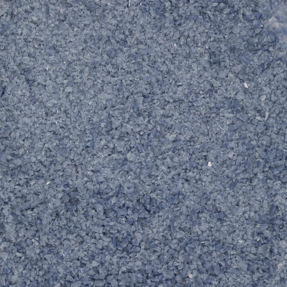 A close-up texture shot of a dark slate blue-gray granular material, showing a fine, chunky crystalline structure.