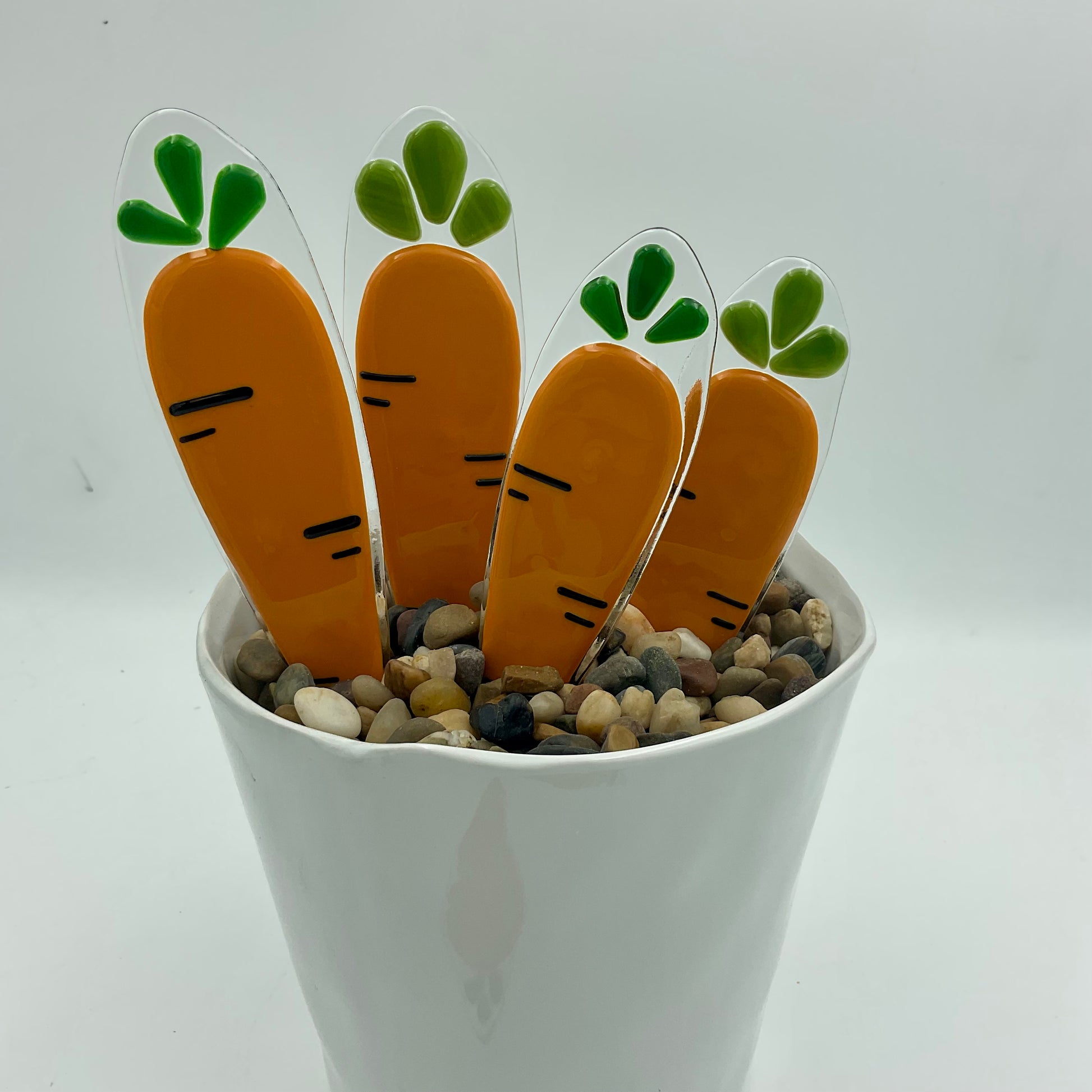 Fused glass carrot plant stakes in a pot.