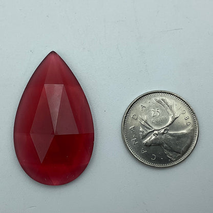A gold-pink faceted teardrop shaped glass jewel.