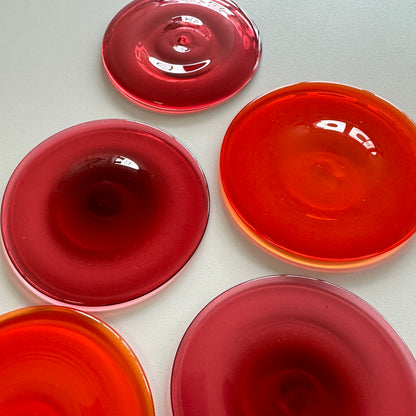 Five pink and orange glass rondels laying on a white surface.