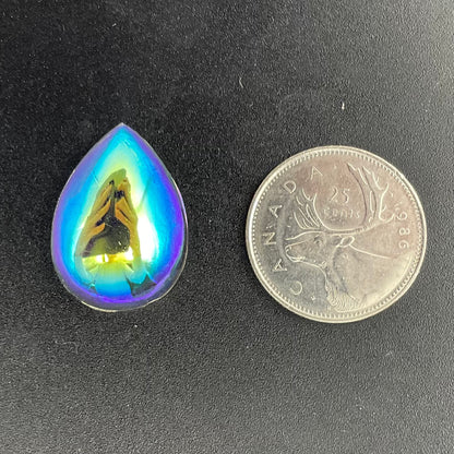 A selection of smooth flat-back teardrop-shaped glass jewels in various colors including clear, red, green, orange, and a trichroic coating with a coin for scale.