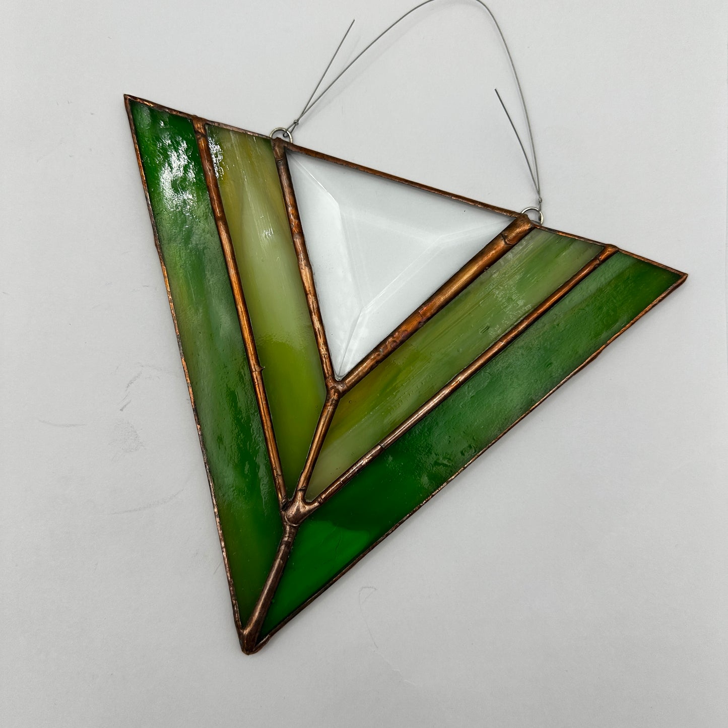 Geometric stained glass panel with green and white colors on a light gray background