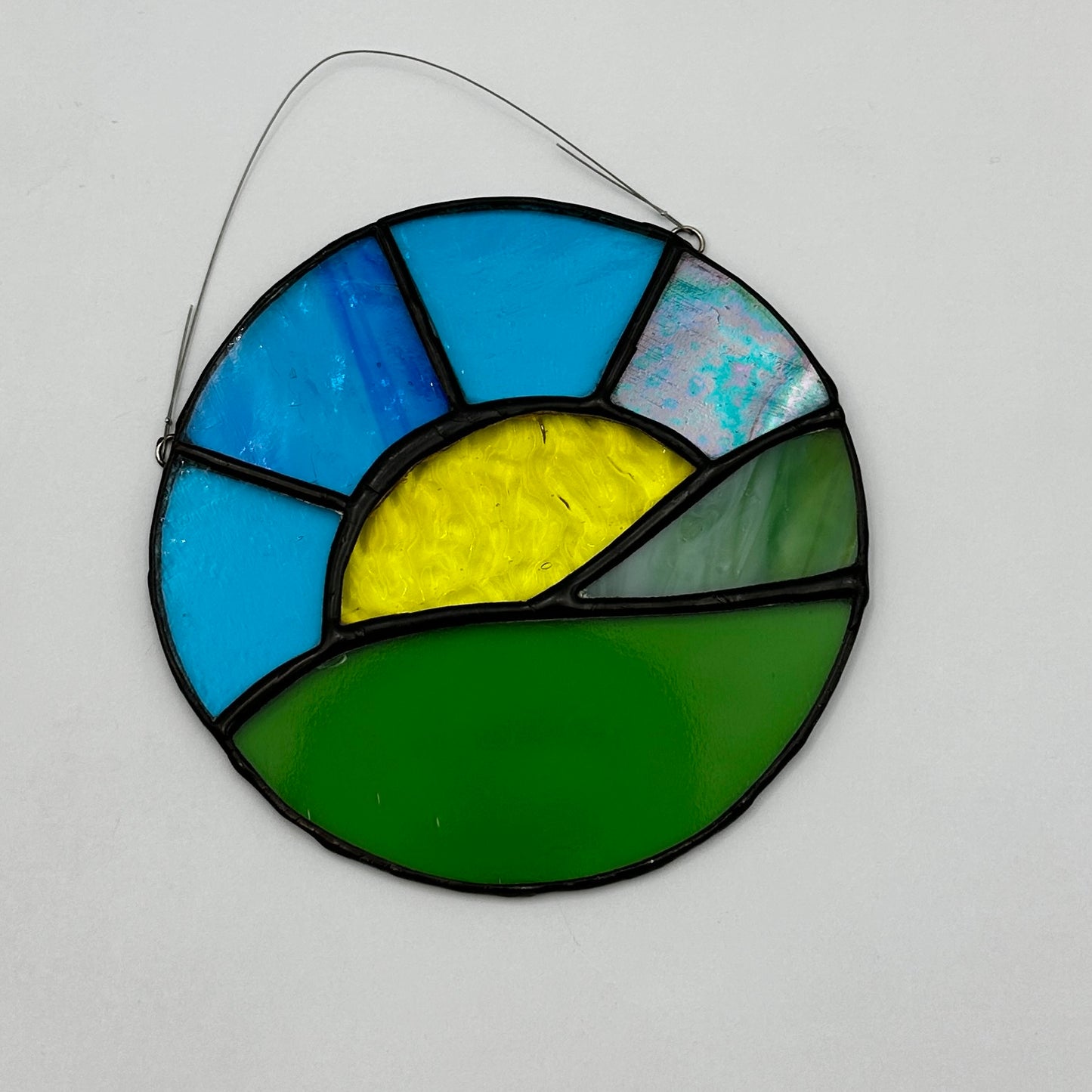 Stained glass suncatcher with blue, yellow, and green colors on a white background