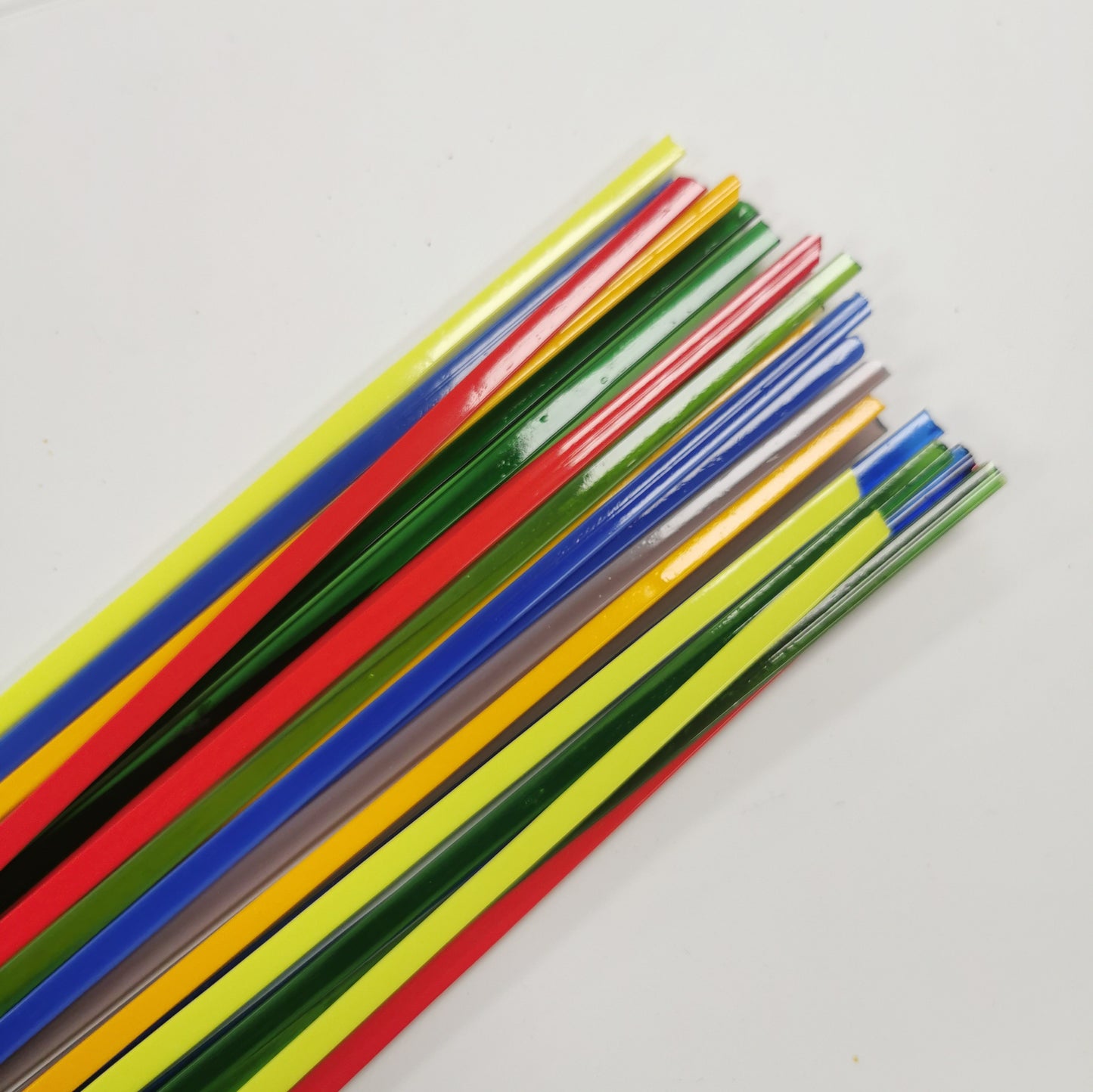 A collection of colorful glass noodles laid out on a white surface, featuring a variety of colors including yellow, red, blue, green, and purple.
