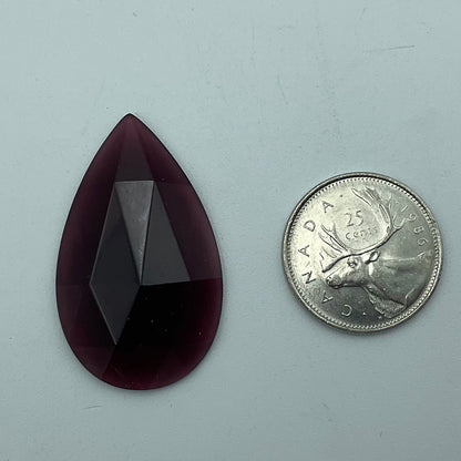 A purple faceted teardrop glass jewel.