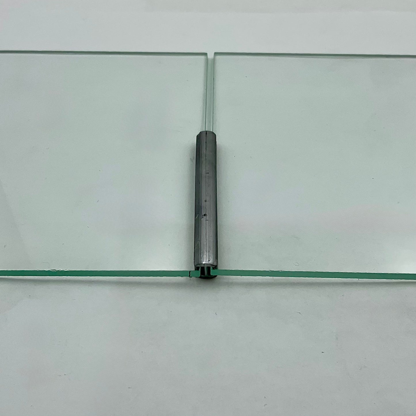 Glass panel with a central metal hinge on a white background