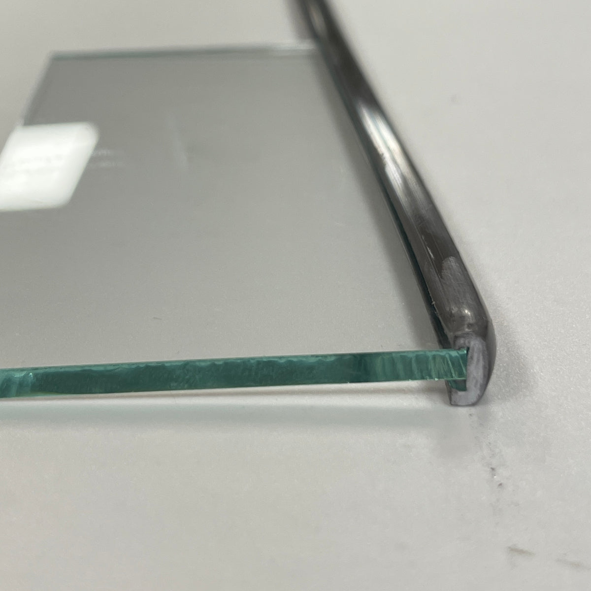 A piece of clear glass with a metal border lead, placed on a white surface.