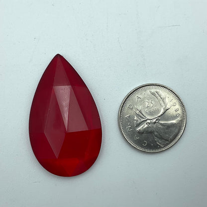 A red faceted teardrop glass jewel.