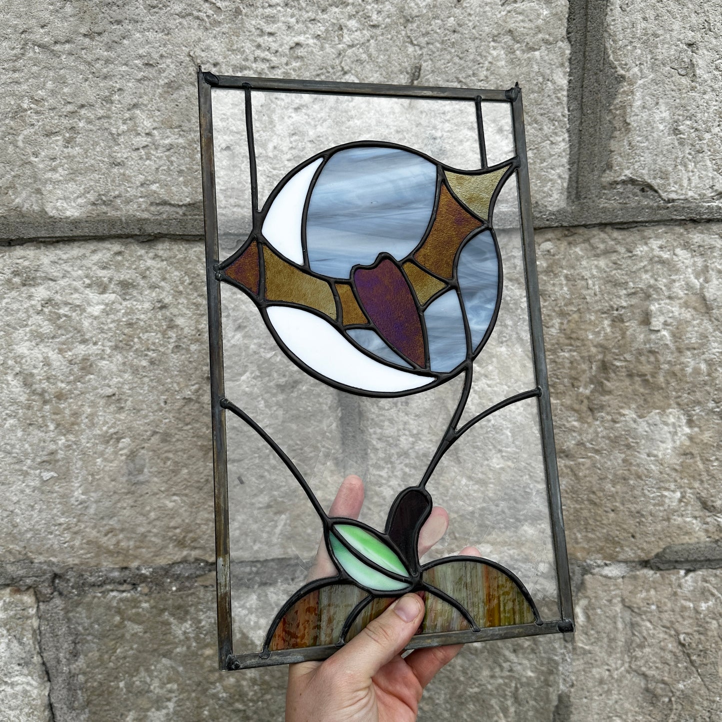 Stained glass panel held against a stone wall