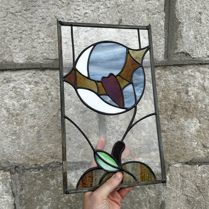 Stained glass panel held against a stone wall