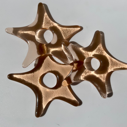 Three pink fused glass star ornaments.