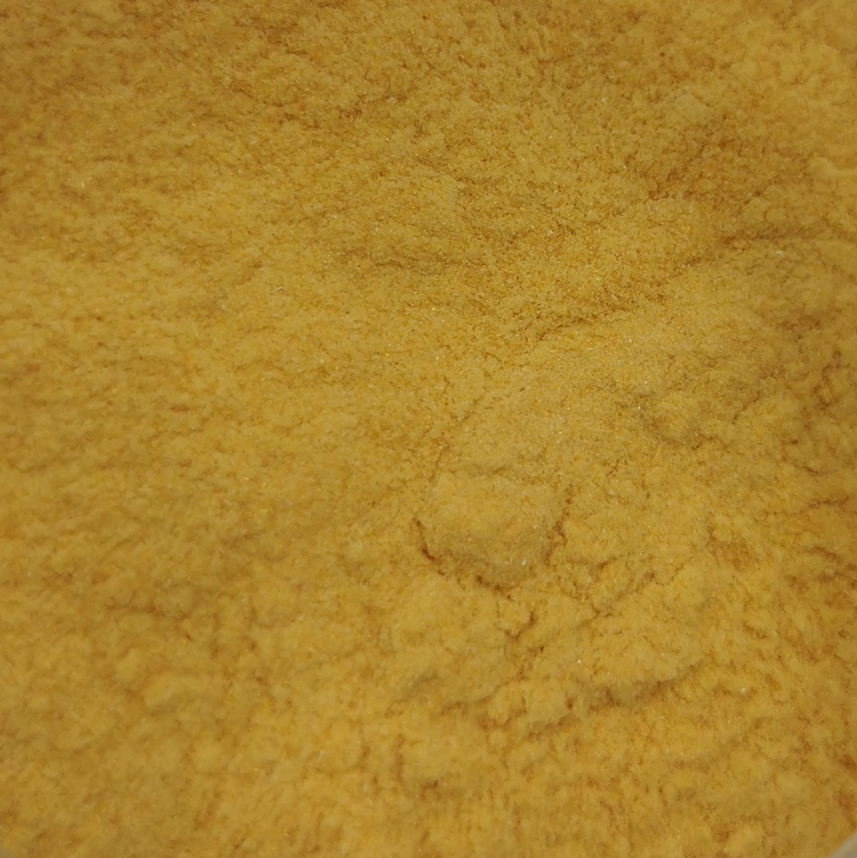 A close-up of a bottle filled with yellow-colored frit, which is a type of opal used in glassmaking.