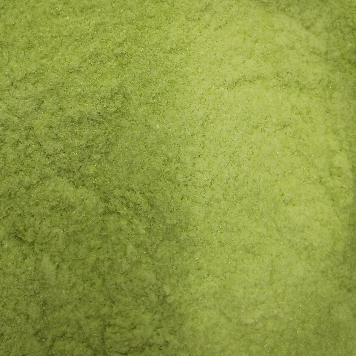Close-up of moss green transparent frit, showing texture and color.