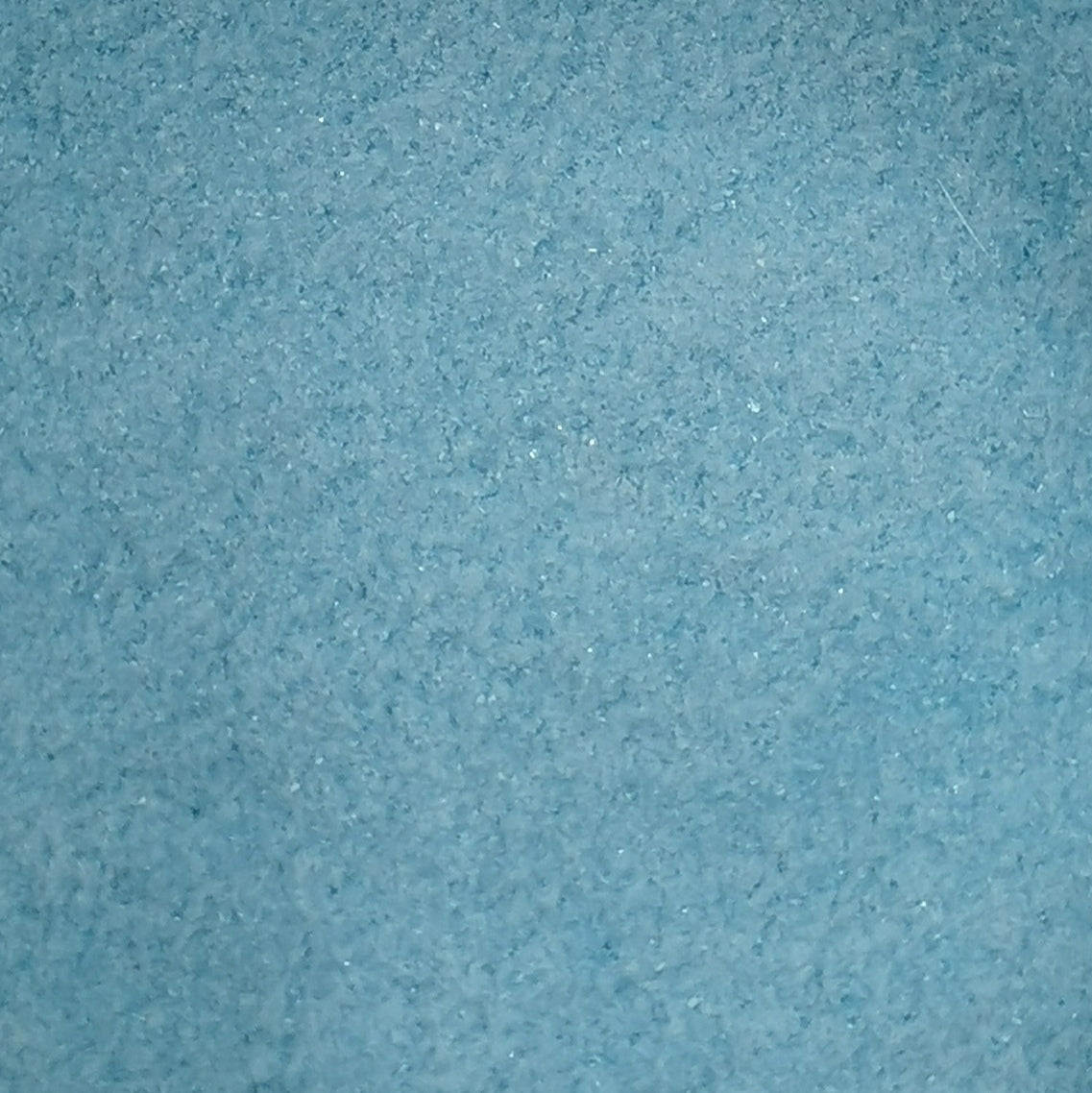 Close-up of a blue frit, likely a glass material used in crafting.