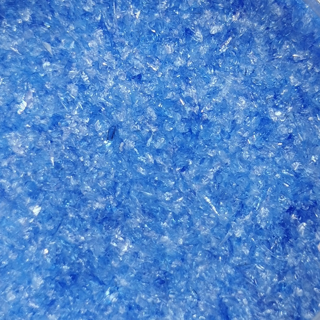 Close-up of light blue transparent frit, showing granular texture.