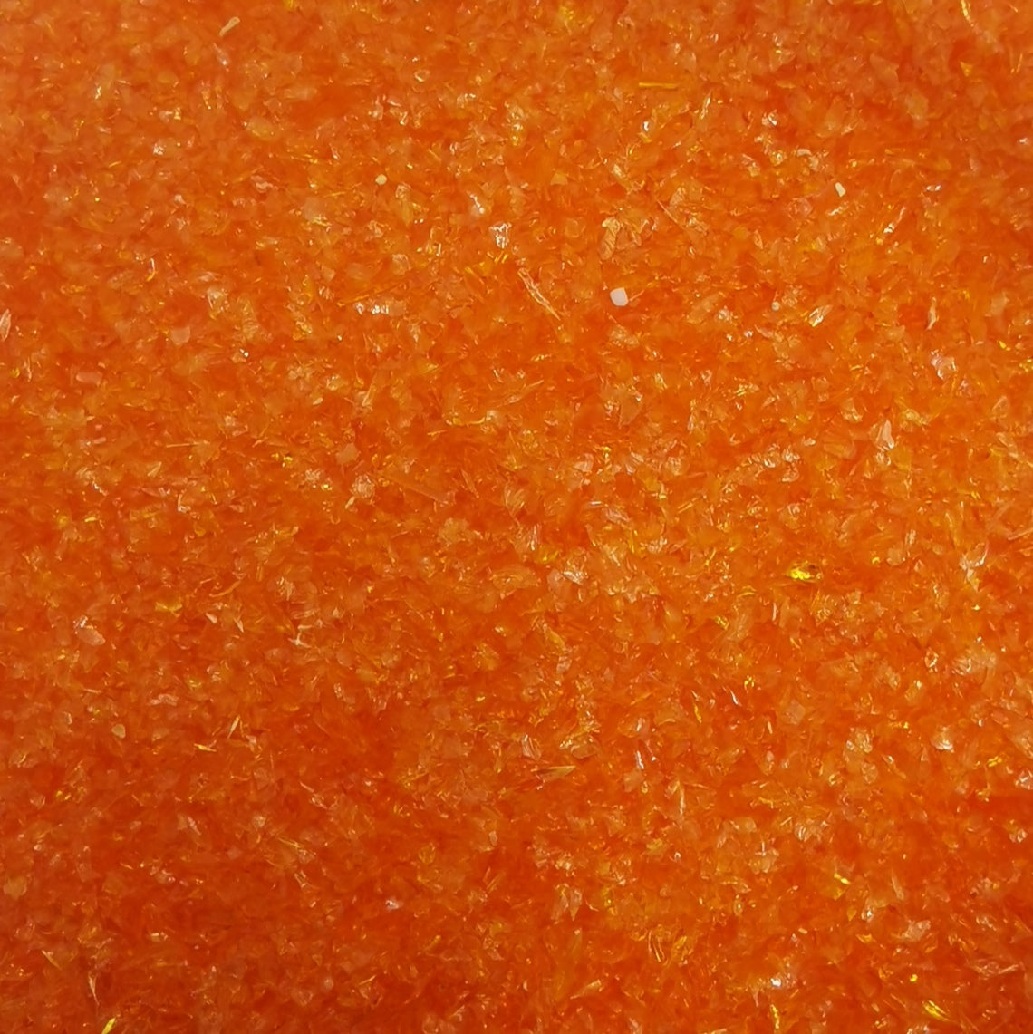 Close-up view of an orange transparent frit used in glass crafting.