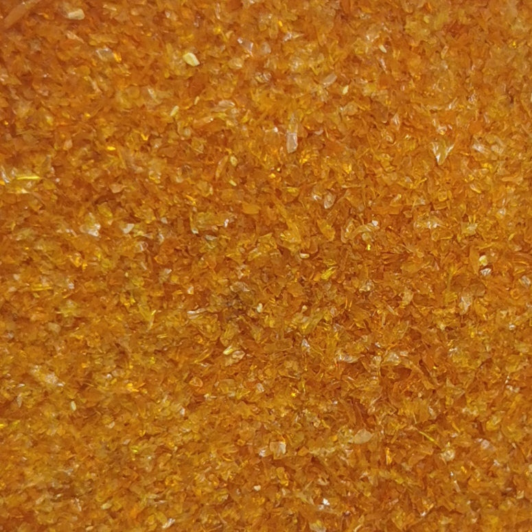 A close-up of a bottle filled with yellow-colored frit, which is a type of opal used in glassmaking.