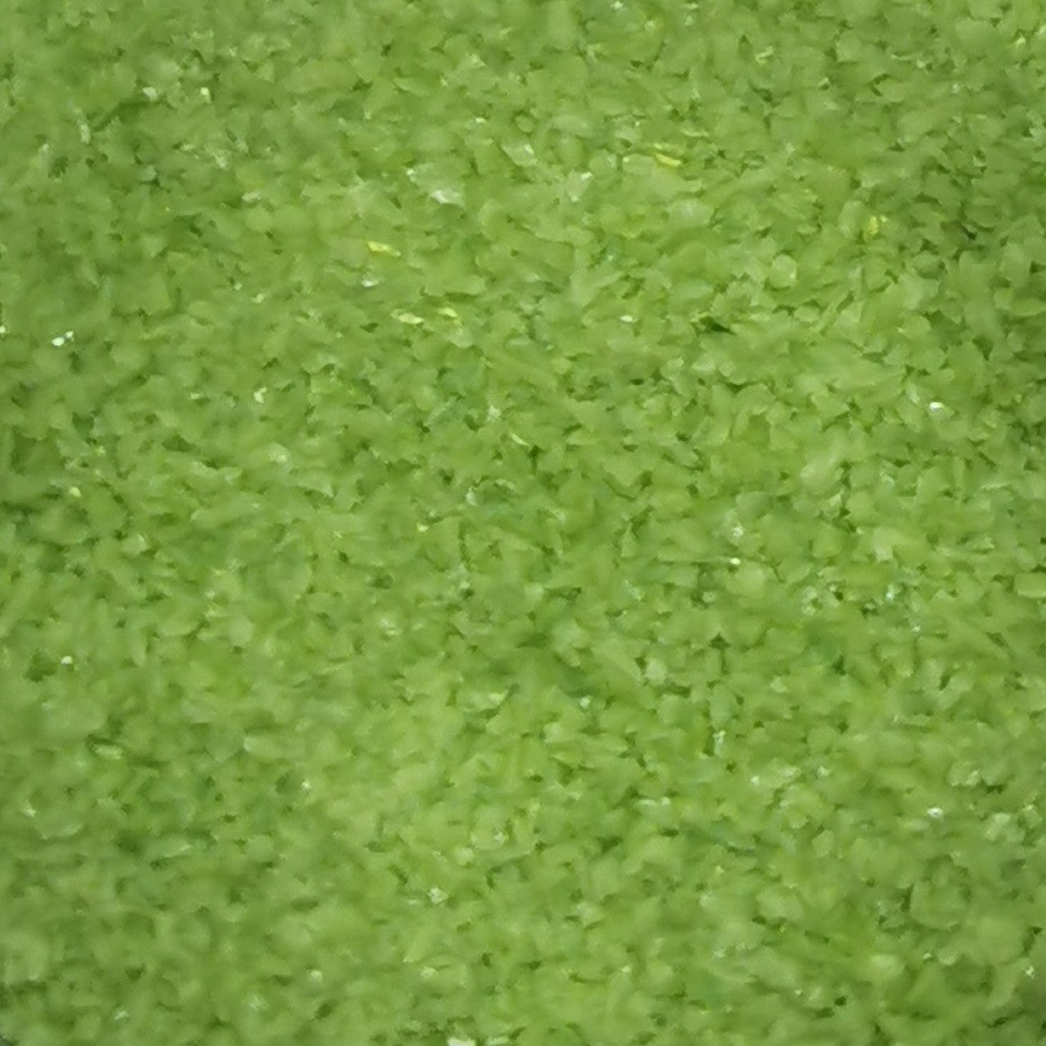 Close-up of an 8oz bottle of OGT Amazon Green Opal 2264 System 96 frit, showing the texture and green color of the material.