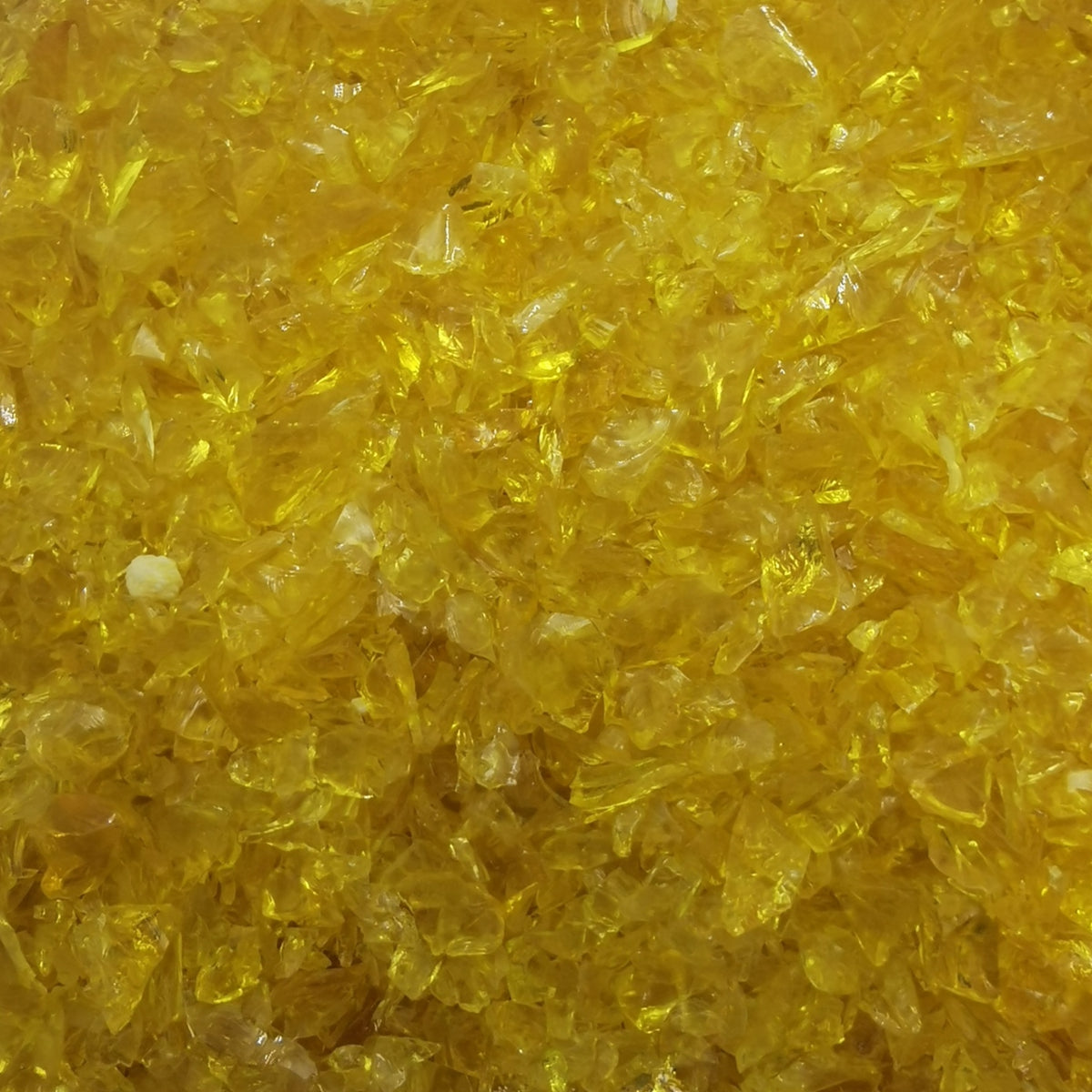 A close-up view of yellow transparent frit, commonly used in glass crafting.