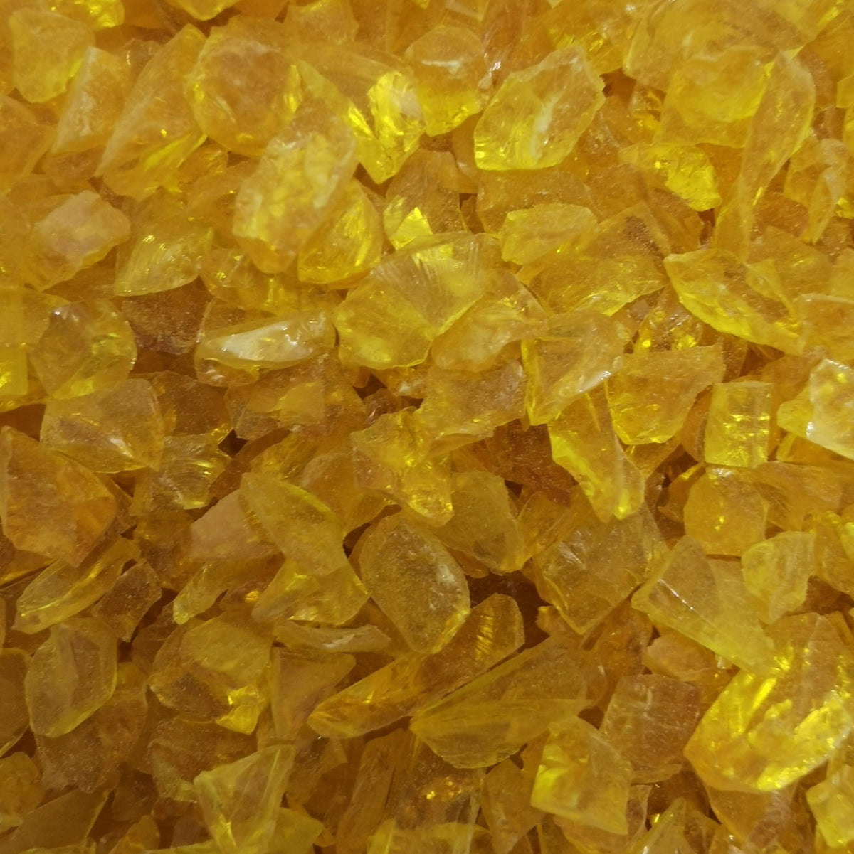 A close-up view of yellow transparent frit, commonly used in glass crafting.