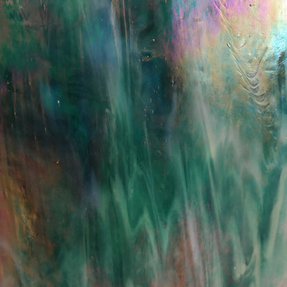 A close-up image of a teal colored non-fusible art glass with an iridescent finish displaying a range of colors including purple and green.