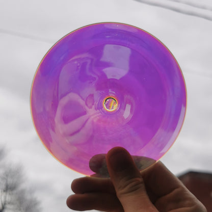 A trichroic glass rondel for stained glass work, backlit.