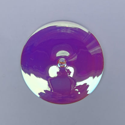 A trichroic glass rondel for stained glass work, frontlit.